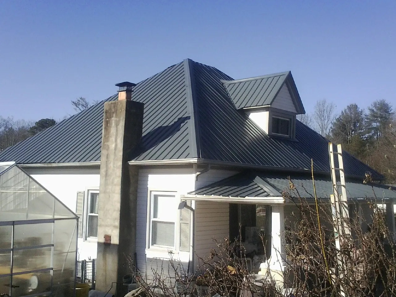 Dark blue standing seam metal roof on a white farmhouse with dormer — Slate & Tile Roof Repair by Roofing Brothers in Rupert