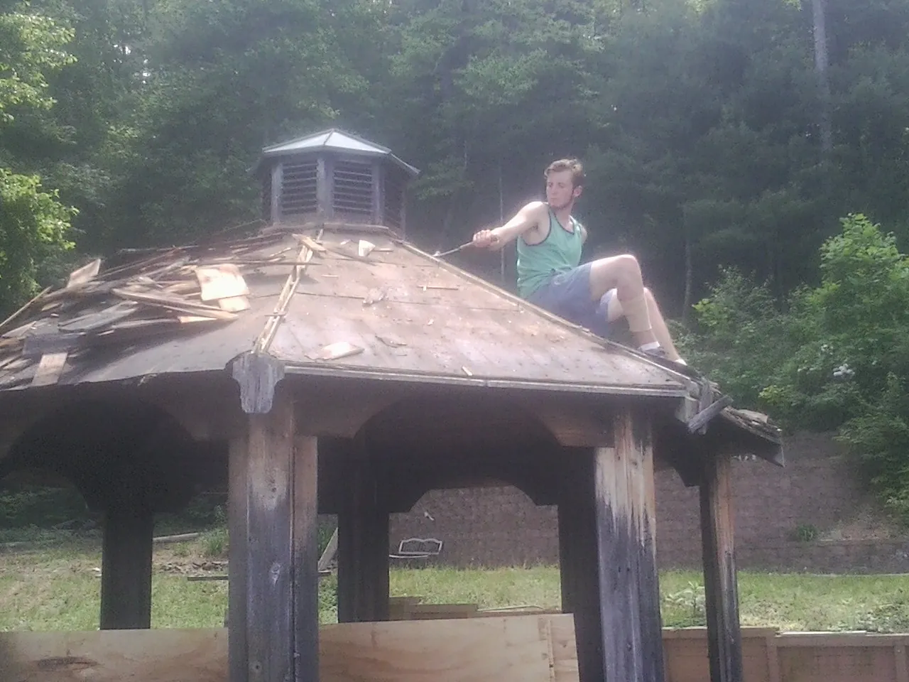 Tearing the old roof off a wooden gazebo before new shakes in Rupert