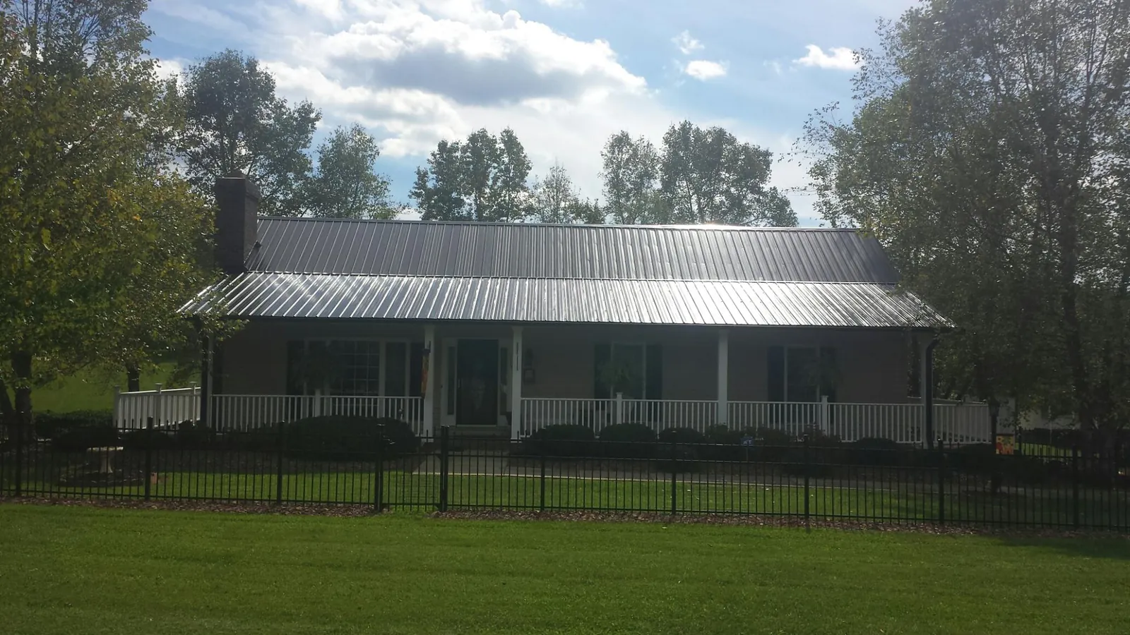 Gray metal roof on a brick ranch with a full width front porch — Gutter Guard Installation work by our crew in Rupert