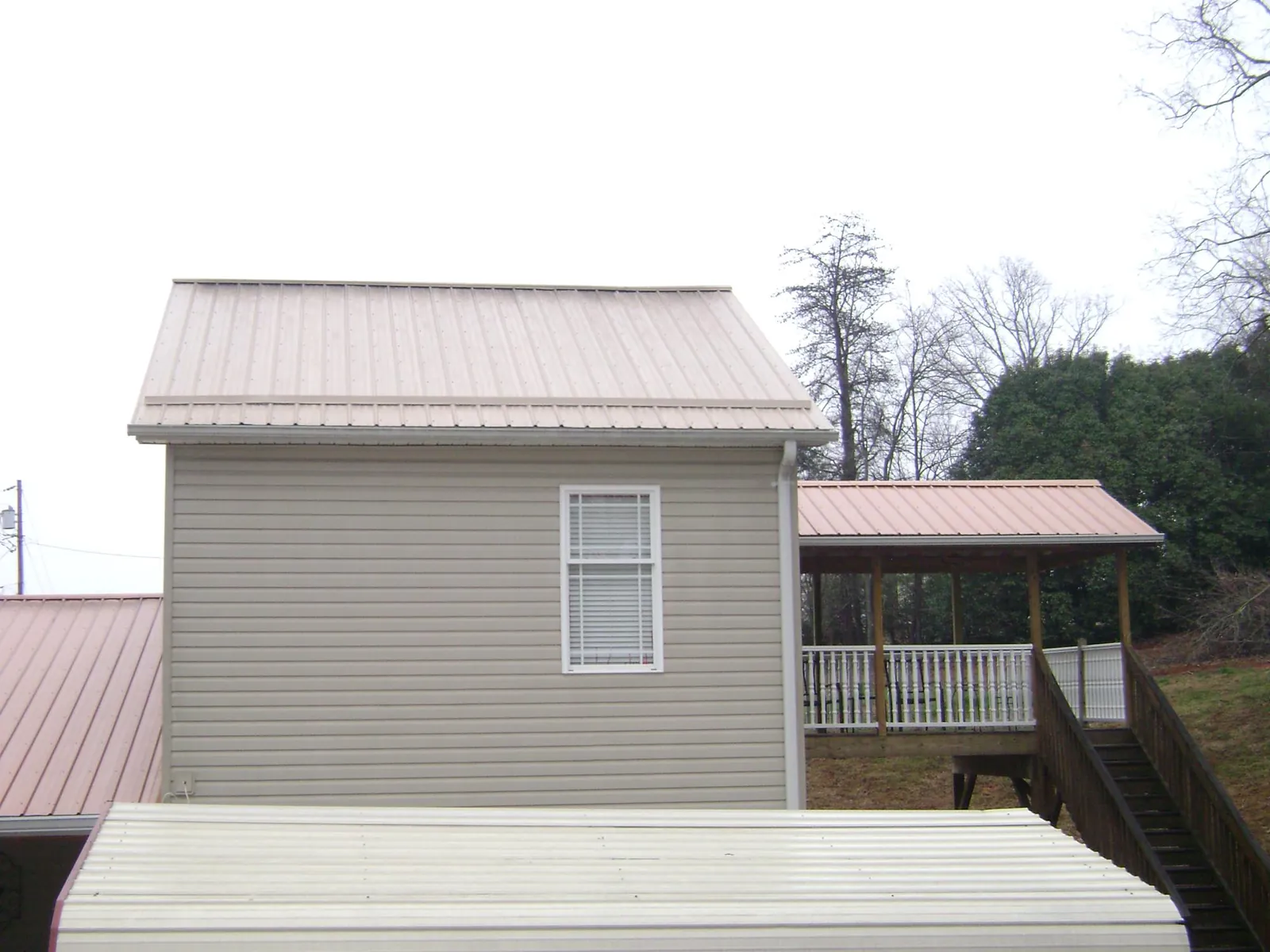 Tan metal roofs on a two story addition and attached porch, from a Roof Replacement job in Rupert